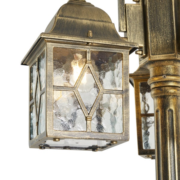 Nahaufnahme einer klassischen Außenleuchte in Gold-Antik-Optik mit strukturiertem Glas und Rautenmuster.