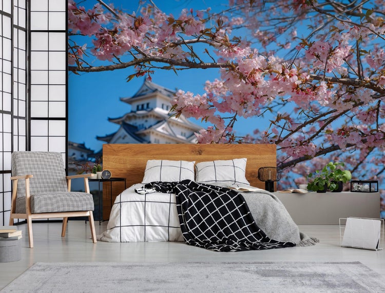 Dekoratives Schlafzimmer mit Bett, Nachttisch und Blick auf die blühende Natur