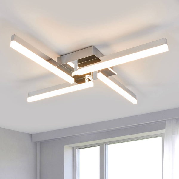Moderne LED-Deckenleuchte mit vier überkreuzten Leuchtstäben aus Metall, montiert an der Decke in einem hellen Raum.