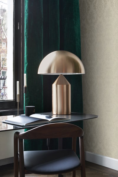 Dekoratives Arbeitszimmer mit Tischleuchte, Schreibtisch und Stuhl vor einem Fenster mit Vorhängen.