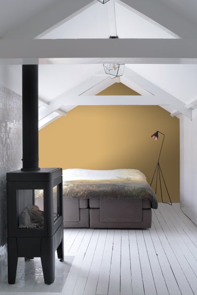 Schlafzimmer mit Kaminofen, Boxspringbett und Stehlampe in einem Dachgeschoss