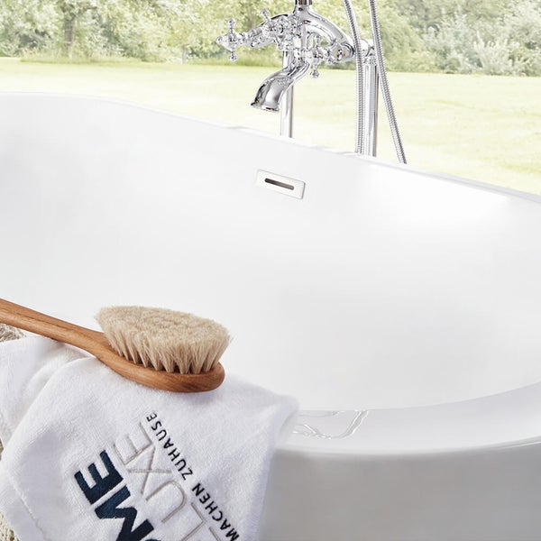 Freistehende Badewanne mit Armatur im klassischen Design und Badebürste mit Handtuch auf dem Wannenrand.