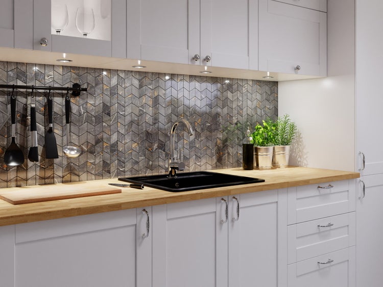 Moderne Küche mit hellgrauen Schränken, Holz-Arbeitsplatte und Chevron-Mosaikfliesen in dunkler Marmoroptik mit schwarzer Spüle.