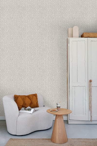 Wohnraum mit Strickmuster-Tapete, Sessel, Beistelltisch und Schrank