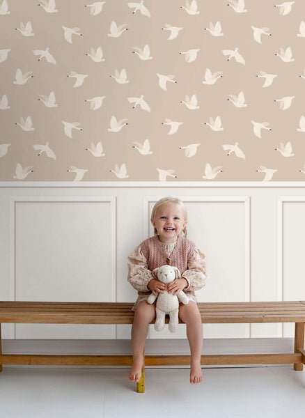 Kindersitzbank vor einer Wand mit Tapete mit Vogelmotiv in einem hellen Kinderzimmer.