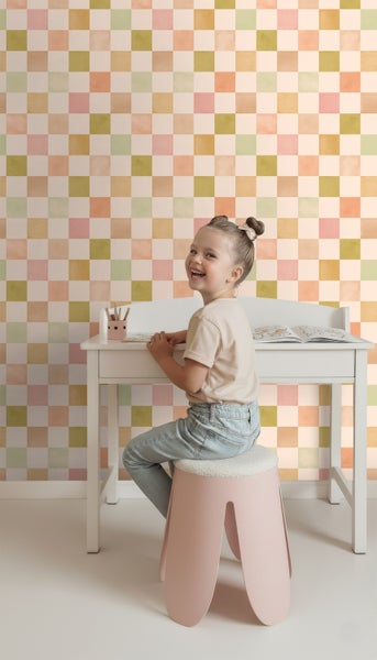 Mädchen am Schreibtisch mit karierter Tapete im Hintergrund