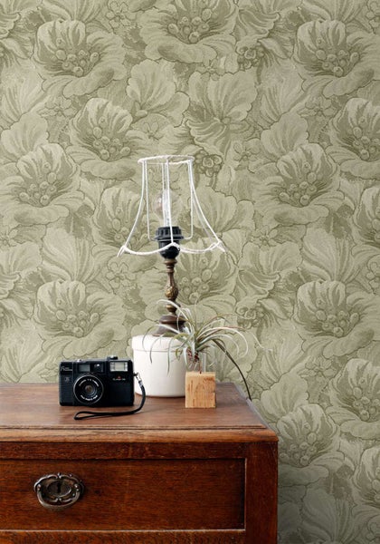 Tapete mit floralem Muster an der Wand hinter einem Holztisch mit einer antiken Lampe und einer Kamera.