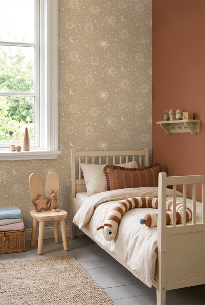 Helles Kinderzimmer mit Vliestapete im Himmelsdesign mit Sonne, Mond und Sternen, einem Kinderbett aus Holz und einem Stuhl mit Hasenohren.