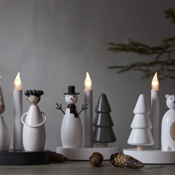 Weihnachtsdekoration mit Holzfiguren und LED-Kerzen auf einem Tisch.