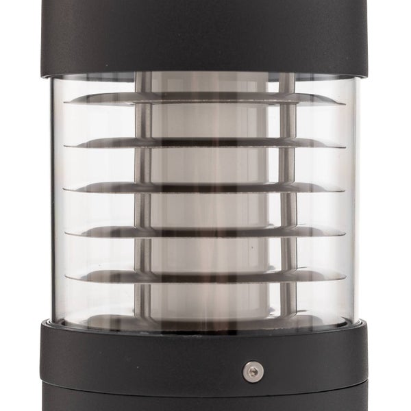 Nahaufnahme einer schwarzen zylindrischen Außenleuchte mit transparentem Glasgehäuse und waagerechten Lamellen im Inneren.