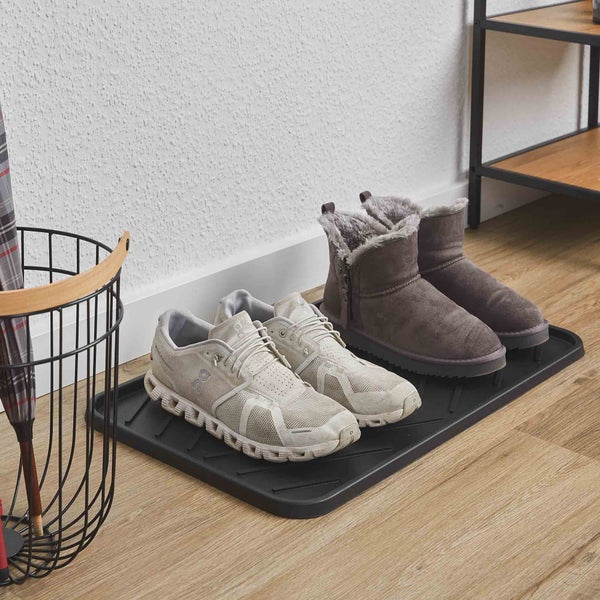 Schwarze Schuhabtropfschale aus Kunststoff mit zwei Paar Schuhen auf einem hellen Holzboden im Eingangsbereich.