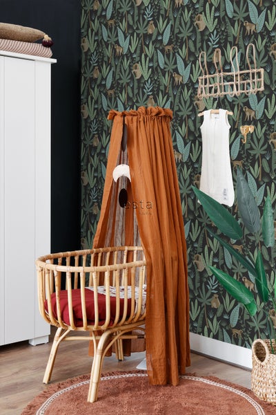 Ein Kinderzimmer mit einem Babybett mit Baldachin, einer Tapete mit Dschungelmotiven und dekorativen Elementen.