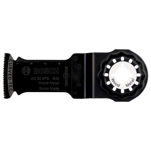 Eine Hand mit Handschuh schneidet mit einem Multifunktionswerkzeug eine Öffnung in eine Wand neben einer bereits installierten Gerätedose.