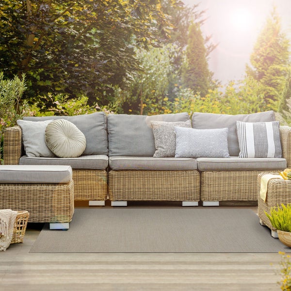 Terrasse mit Rattansofa, Kissen und Outdoor Teppich