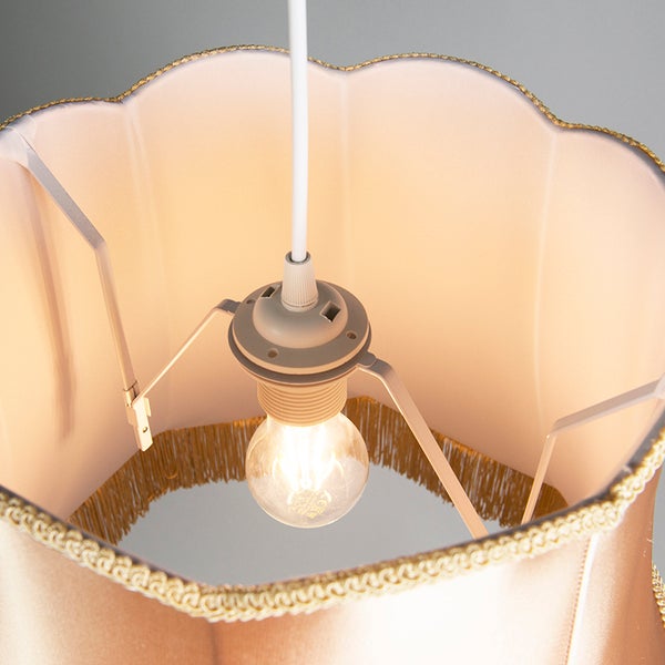 Innenansicht eines klassischen Lampenschirms aus Stoff mit gewelltem Rand, goldener Borte und brennender Glühbirne.