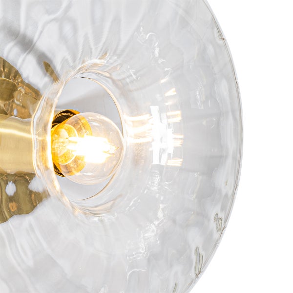 Detailansicht einer Lampe mit klarem Glas und goldfarbener Fassung