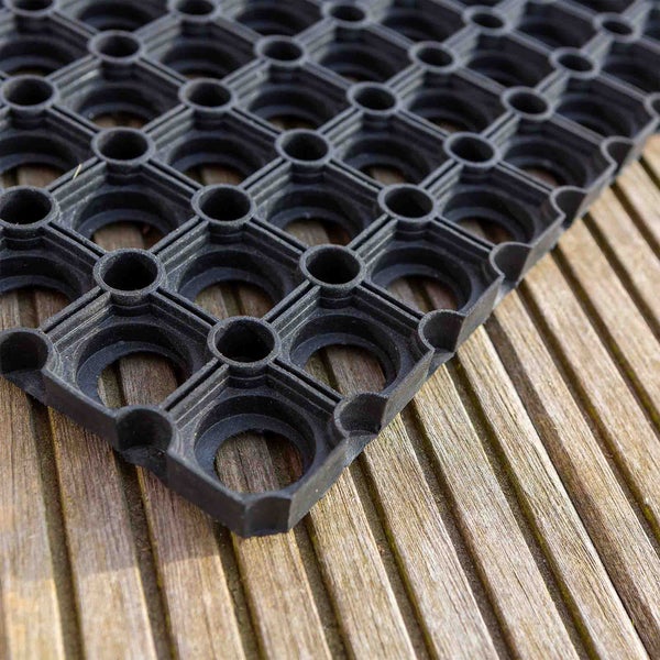 Schwarze Gummimatte mit Lochmuster auf Holzboden