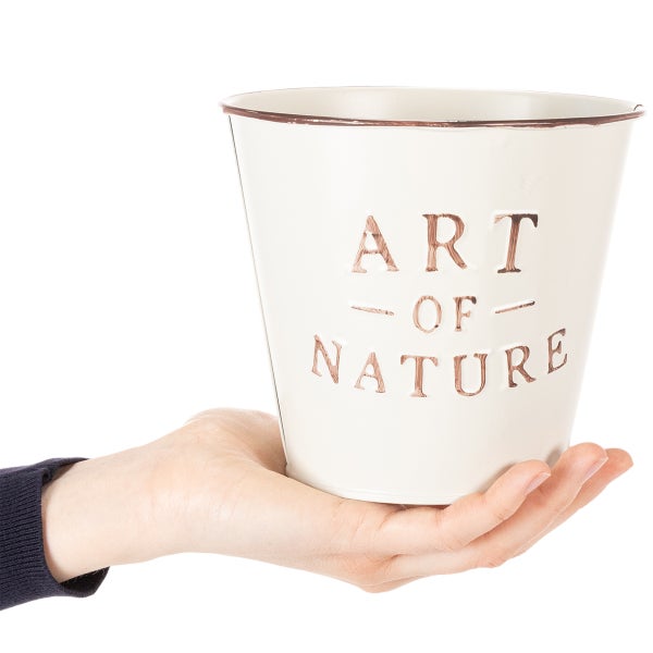 Kleiner Übertopf aus Metall in Weiß mit Kupferrand und geprägtem Schriftzug Art of Nature, zur Veranschaulichung der Größe in einer Hand gehalten.