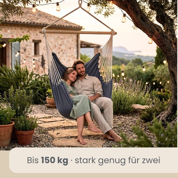 Paar in einem Hängesessel aus Stoff mit Holzstab im Garten. Belastbar bis 150 Kilogramm, Platz für zwei Personen.
