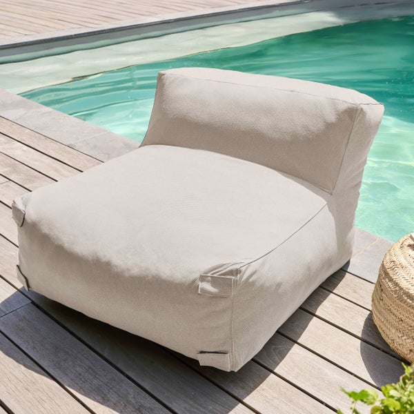 Beiger Outdoor-Sitzsack aus strukturiertem Stoff auf einer Holzterrasse neben einem Swimmingpool.