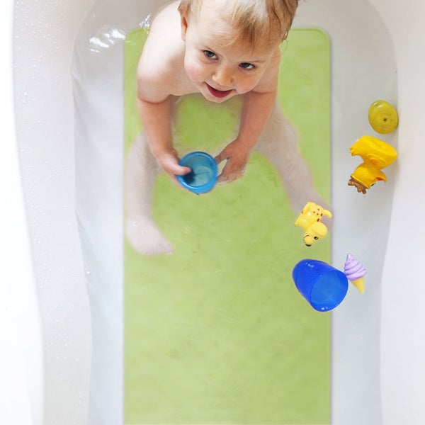 Ein Kind sitzt in der Badewanne mit einer grünen Antirutschmatte und Spielzeug.