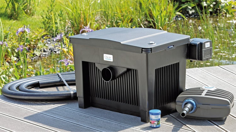 Oase Teichfiltersystem mit Pumpe, Schlauch und Filterstarter auf einem Holzsteg an einem Gartenteich.