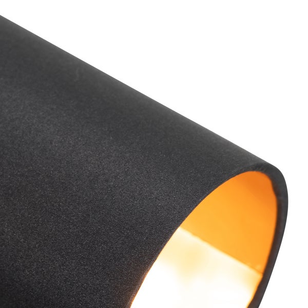 Detailaufnahme eines Lampenschirms aus schwarzem Textil mit goldfarbener Innenseite.
