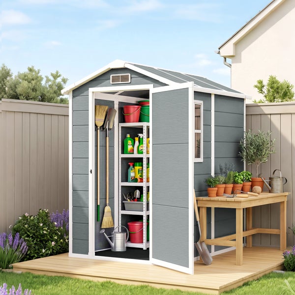 Gartenhaus mit offenem Eingang, Regalsystem und Werkzeugausstattung auf einer Holzplattform im Garten mit angeschlossenem Arbeitstisch.