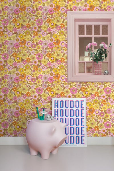 Raumansicht mit floraler Tapete, Fenster, rosa Sparschwein und Poster.