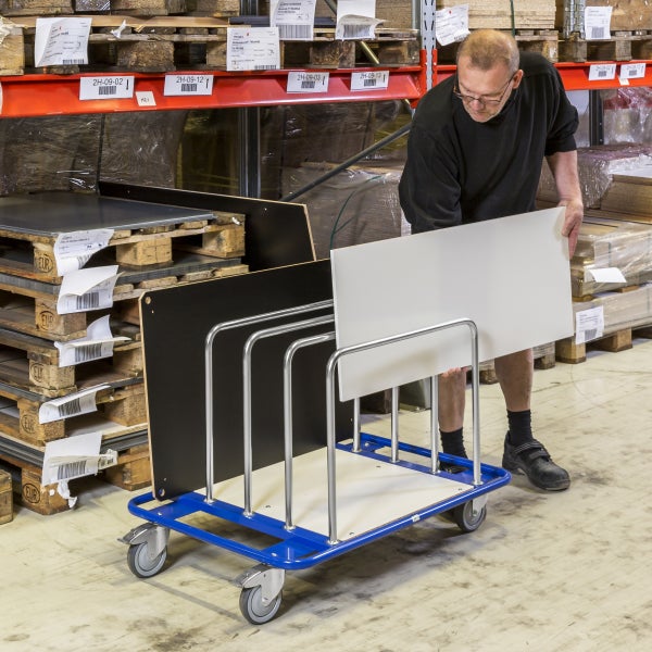 Ein Mann bestückt einen Transportwagen mit Plattenmaterialien in einem Lager