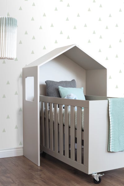 Kinderbett mit Hausstruktur und Rädern im Kinderzimmer.