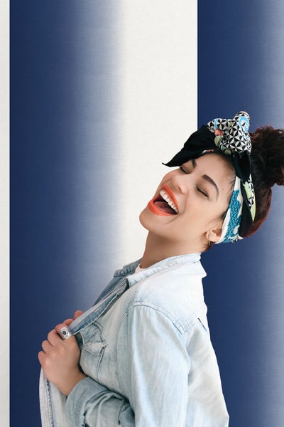 Frau mit gemustertem Haarband und Jeansjacke lächelt