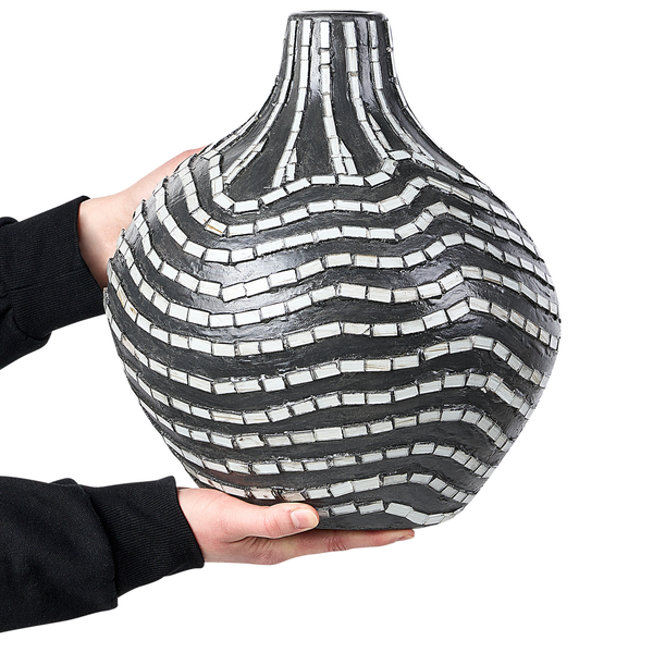 Dekorative Vase mit Mosaikmuster in Wellenoptik, gehalten von zwei Händen.