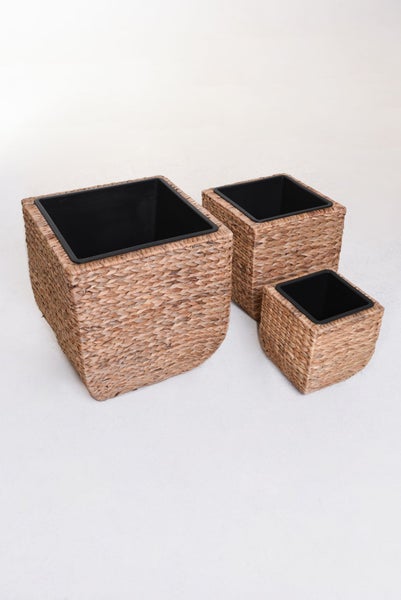 Dreiteiliges Set quadratischer Pflanzkübel aus geflochtener Naturfaser mit schwarzen Kunststoffeinsätzen in verschiedenen Größen.