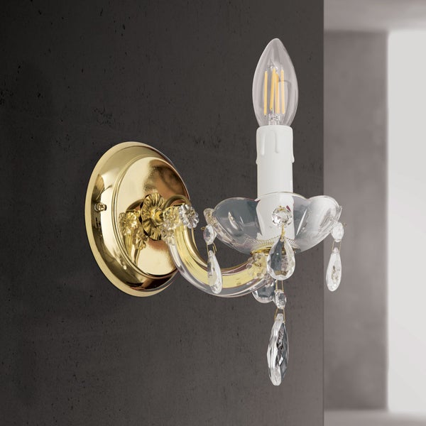 Klassische Wandleuchte in Kerzenform mit Kristallbehang und goldfarbener Wandhalterung montiert an einer Wand