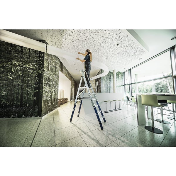 Frau auf einer Stufenleiter bei Deckenarbeiten in einem Bürogebäude