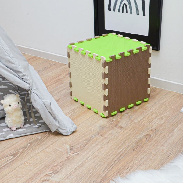 Würfel aus ineinandergreifenden Schaumstoffmatten auf einem hellen Boden in einem hellen Kinderzimmer neben einem Spielzelt.