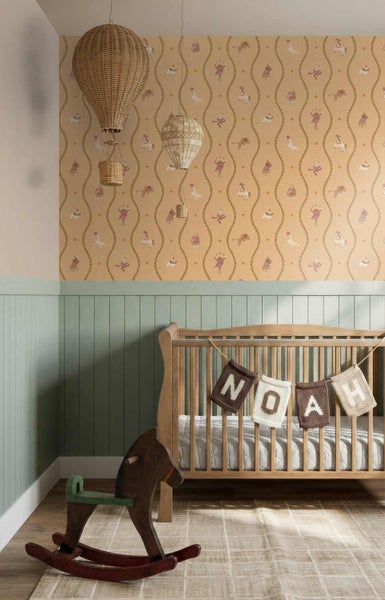 Kinderzimmer mit Zirkus-Vliestapete, grüner Wandvertäfelung, einem Holz-Gitterbett und einem hölzernen Schaukelpferd.