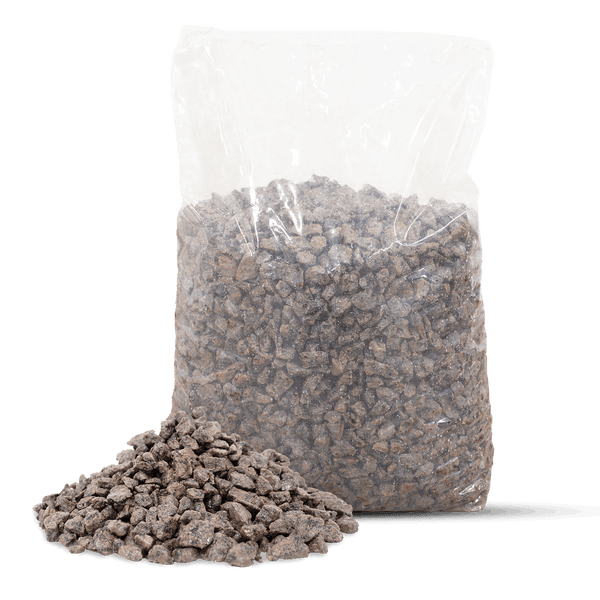 Transparenter Sack mit Ziersplitt und ein kleiner Haufen grau-brauner Natursteine im Vordergrund.