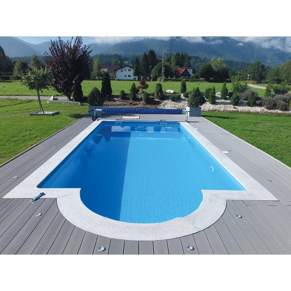 Eingebauter Swimmingpool mit blauem Wasser und grauer Terrassenumrandung sowie Poolabdeckung in einem Garten mit Bergblick.