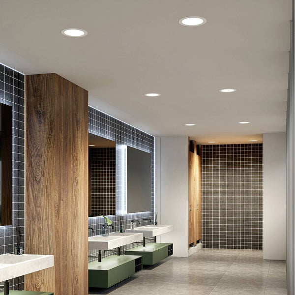 Moderner, heller Waschraum mit runden LED-Einbaustrahlern an der Decke, Wandfliesen, Holzelementen und mehreren Waschbecken.