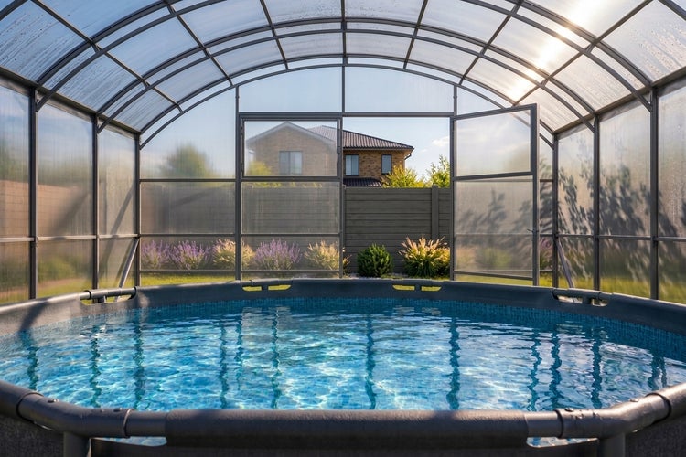 Rundes Aufstellbecken mit Poolüberdachung im Garten vor einem Wohnhaus.