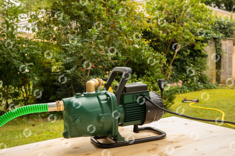 Gartenpumpe auf einem Holztisch im Garten.