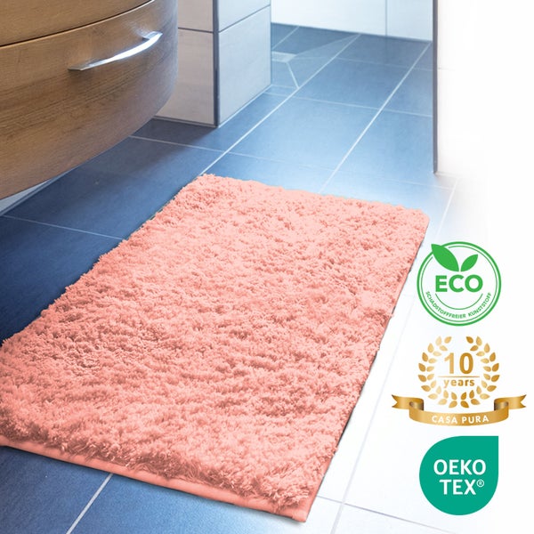 Rosa Badteppich vor einem Badezimmerschrank und Fliesen