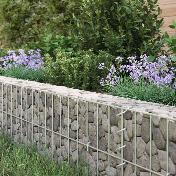Eine Gabionenmauer aus Natursteinen gefüllt mit einem Metallgitterrahmen als dekorative Gartenmauer mit Lavendel im Hintergrund