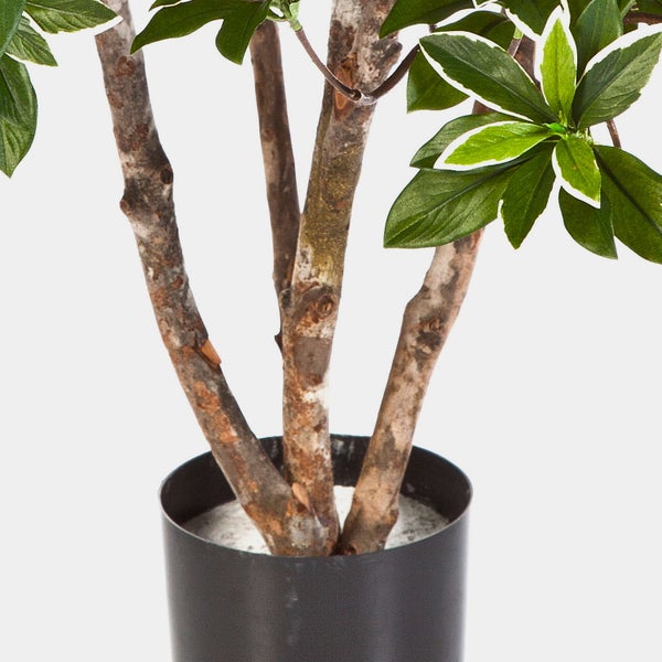 Künstliche Pflanze im schwarzen Topf, Detailansicht der strukturierten Stämme und grünen Blätter.