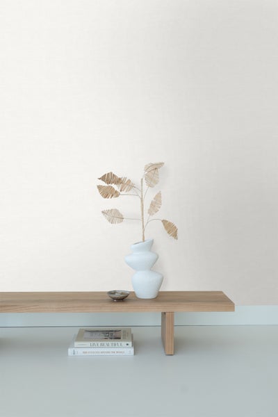 Dekorative Szene mit Vase, Kunstpflanze, Schale und Büchern auf einem Holztisch.