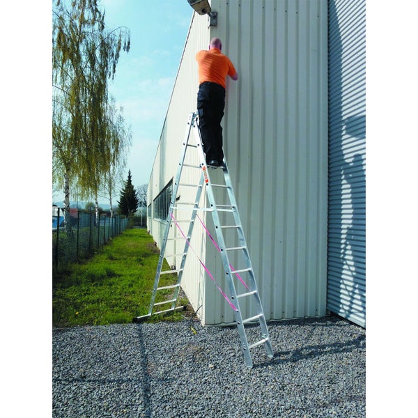 Eine Person steht auf einer Aluminium Anlegeleiter und arbeitet an der Außenwand einer Industriehalle.