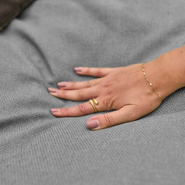 Hand auf einem grauen, strukturierten Stoff.