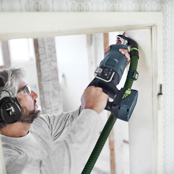 Ein Bauarbeiter bohrt mit einer Bohrmaschine ein Loch in eine Betonwand auf einer Baustelle.